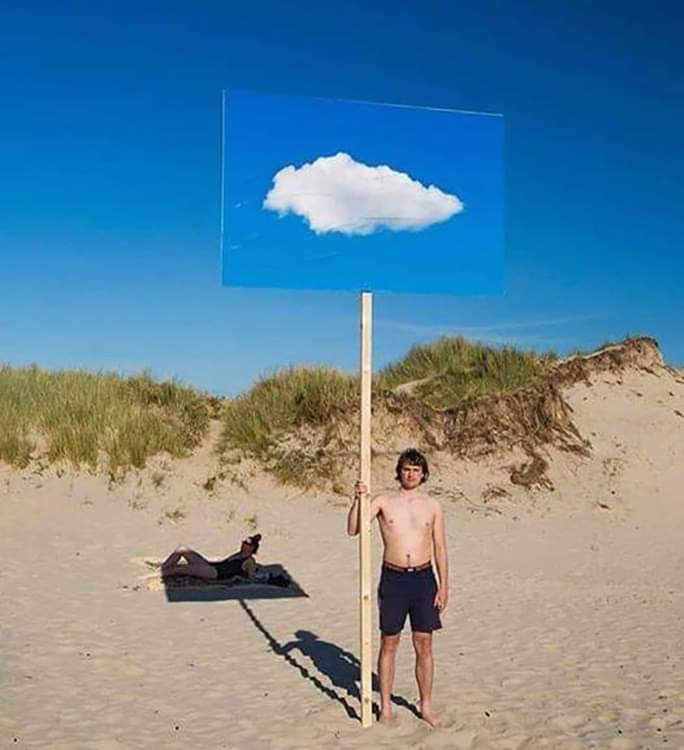 Un homme à la plage avec pancarte d'un nuage sur fond de ciel bleu.