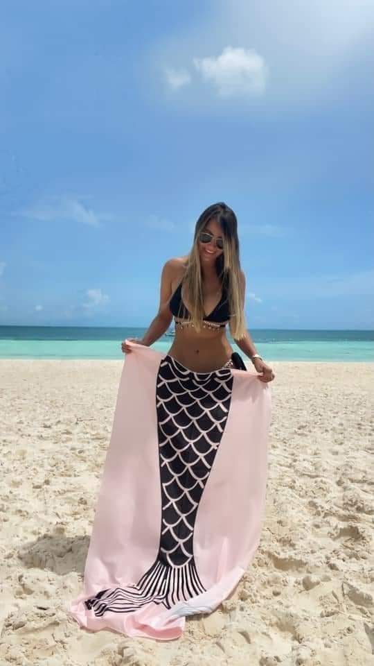 Femme à la plage avec une serviette sirène.