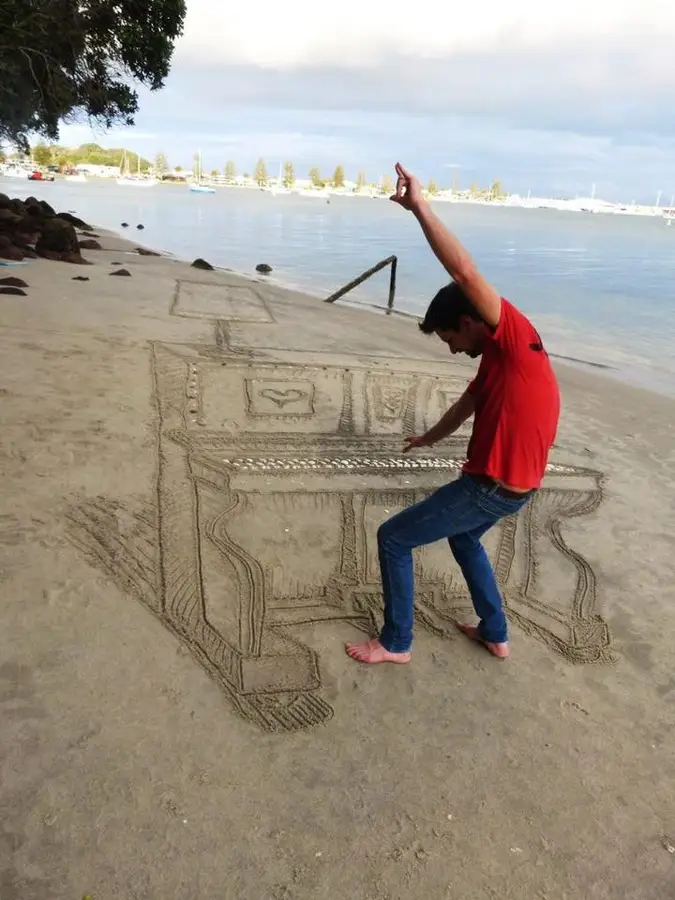 Piano dessiné sur le sable d'une plage.