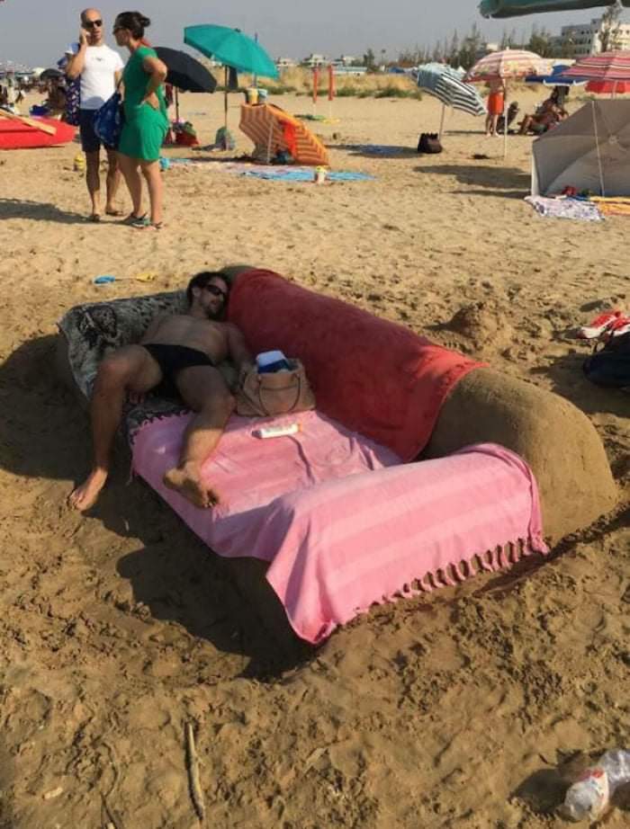 Sculpture sur sable: un homme dort dans un banc de sable.